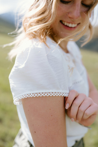 Soft white Hampton Top with delicate lace trim, perfect for casual summer wear at Jamie’s Boutique.