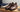 Polished brown leather dress shoes on a wooden bench with rolled socks and shoe conditioner