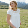 Relaxed Hampton Top with embroidery, worn outdoors in a scenic mountain setting, showcasing casual elegance.